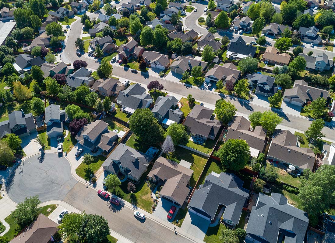 Insurance Solutions - Aerial View of a Quiet Suburban Neighborhood with Homes Surrounded by Green Trees on a Sunny Day